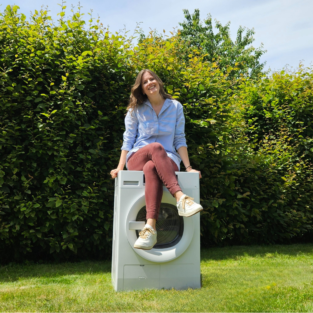 Evelyn sitzt auf einer Waschmaschine in der Natur